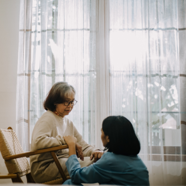 Caregiver looking at her client from below as the client is sitting on the chair