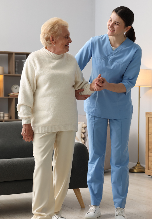 A nurse assists an elderly woman in a cozy living room, providing care and support in a warm environment.