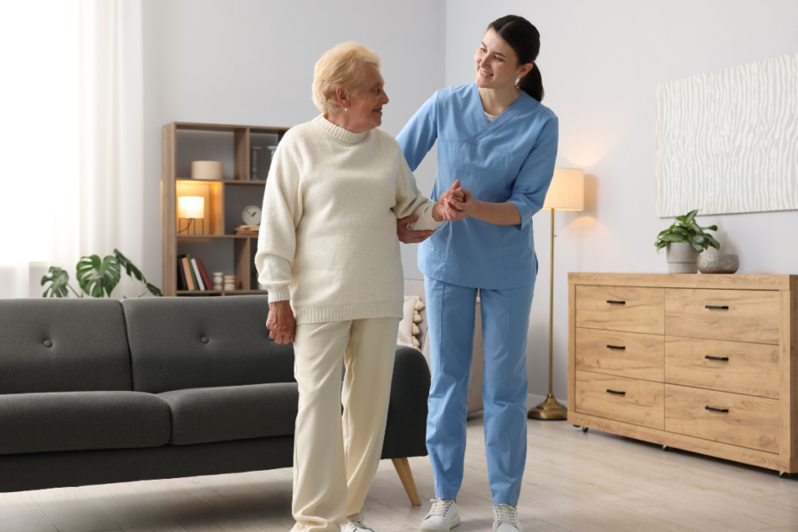 A nurse assists an elderly woman in a cozy living room, providing care and support in a warm environment.