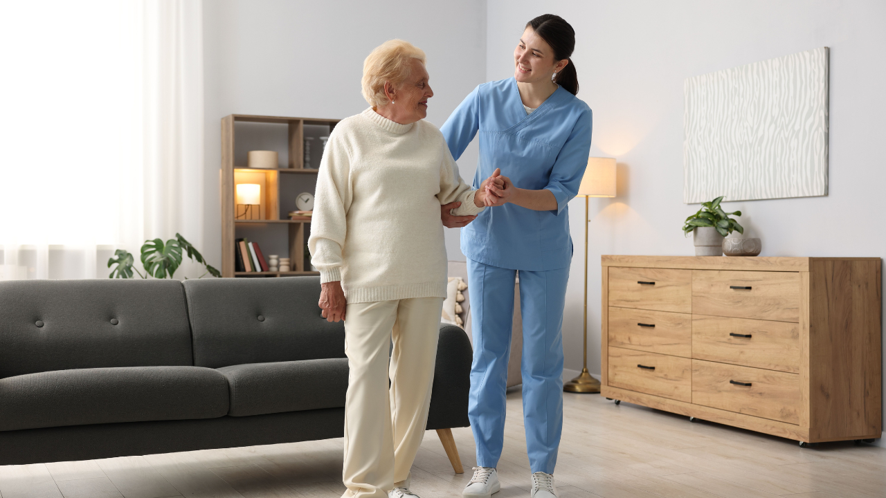 A nurse assists an elderly woman in a cozy living room, providing care and support in a warm environment.