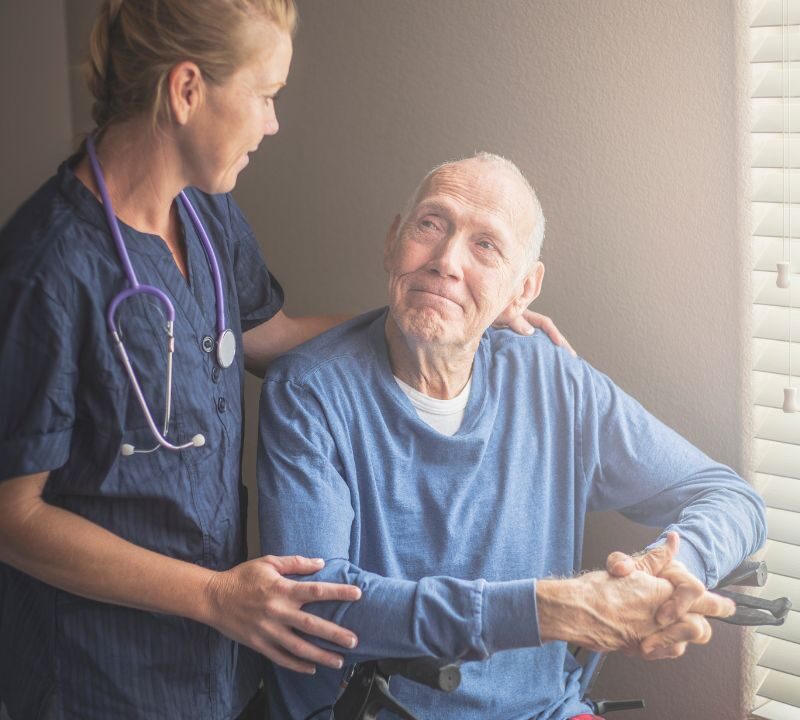 In-home caregiver providing supportive home care to senior man during transitional care period.