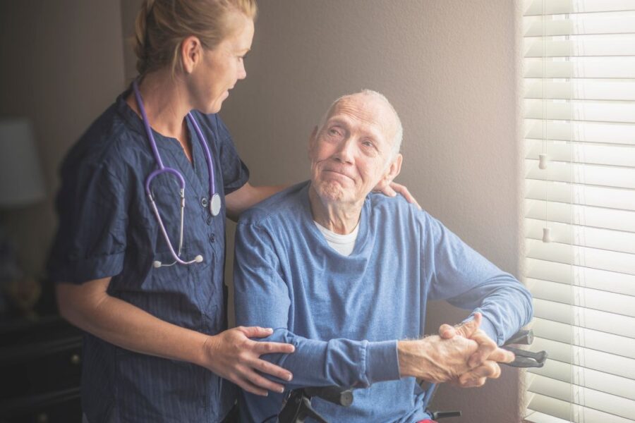 In-home caregiver providing supportive home care to senior man during transitional care period.