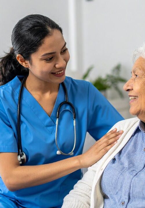 Professional in-home caregiver supporting a senior woman during post-surgery recovery at home.