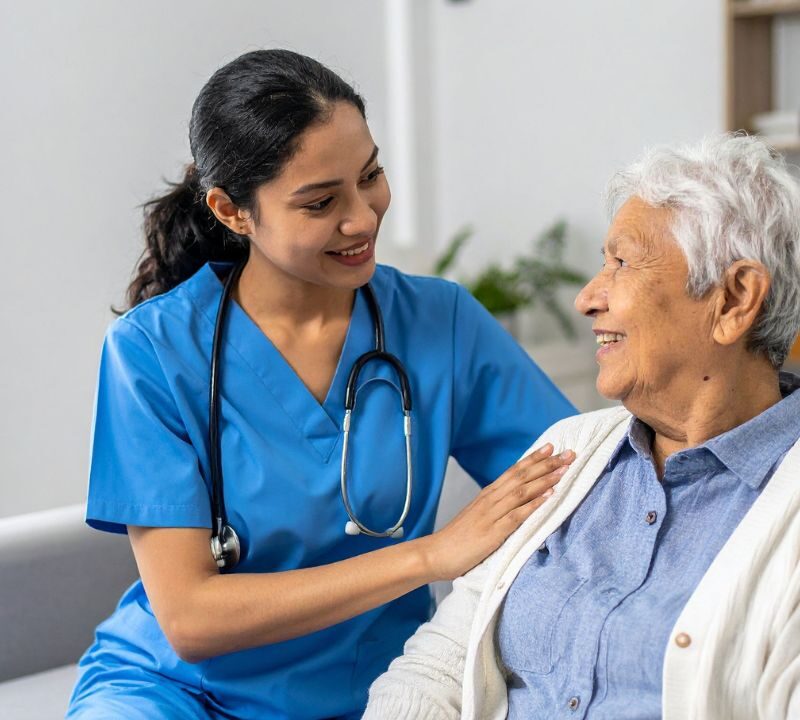 Professional in-home caregiver supporting a senior woman during post-surgery recovery at home.