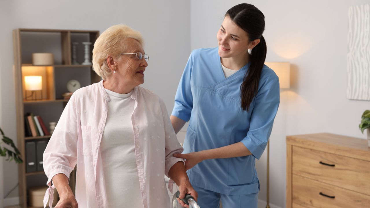 Caregiver assisting an older adult using a walker during in-home care.