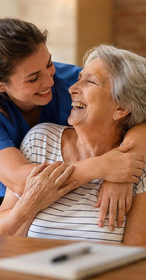 A younger woman hugs an older woman in her home, highlighting a moment of connection and compassion.